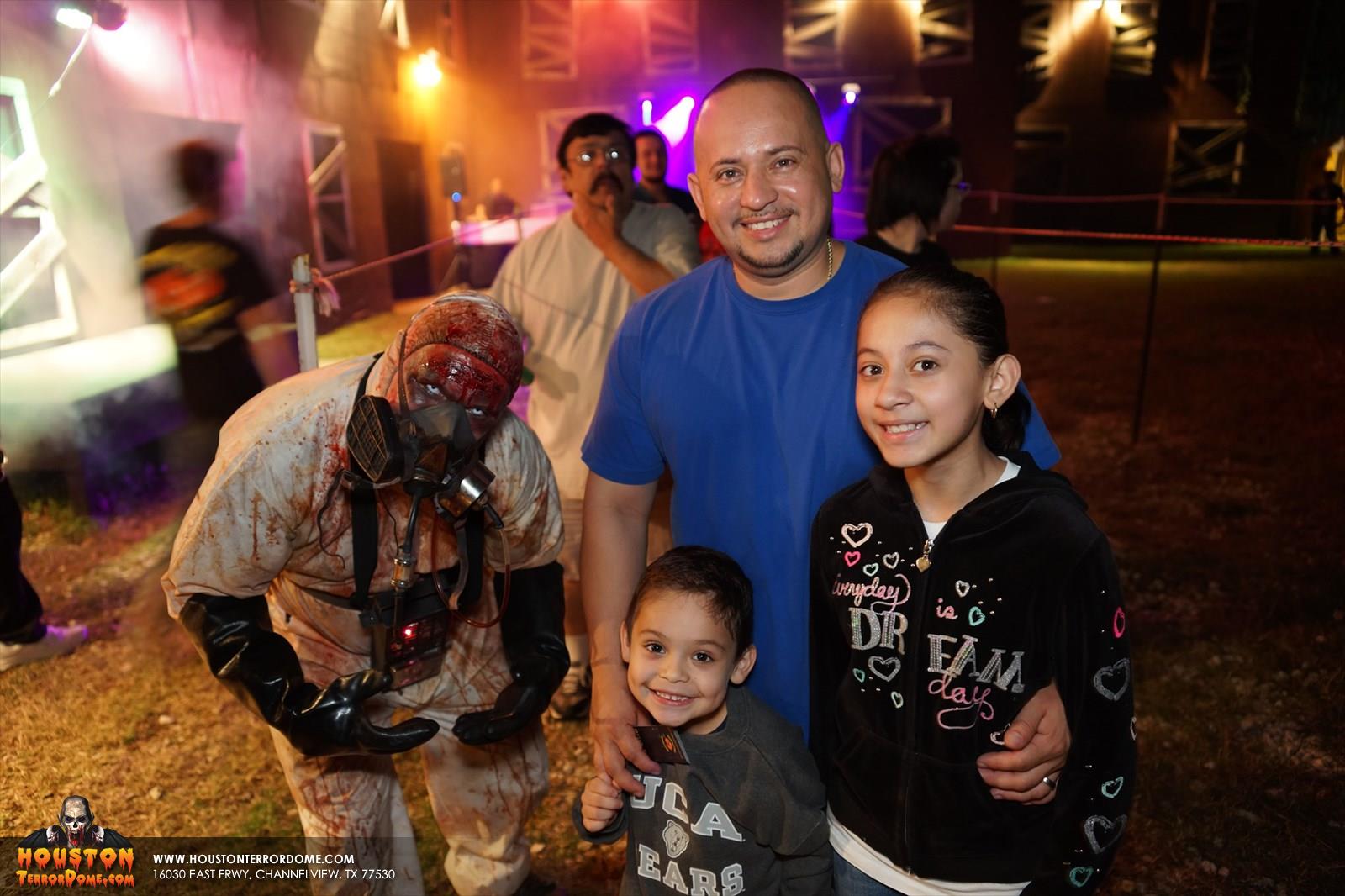 Young kid stays close to dad while waiting in line at the Haunted house