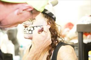 Makeup artist applying makeup to skull actor